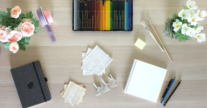 カッター・定規・紙・リボンなどのDIY用ツールを机に並べて準備している様子。